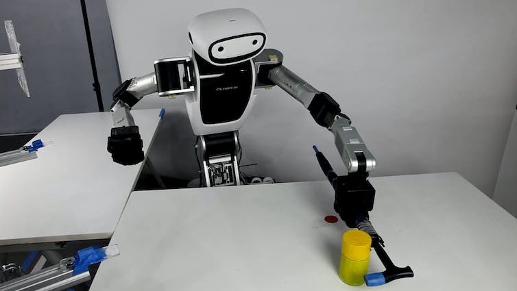 robot saisissant un marteau pour faire glisser un objet sur une table